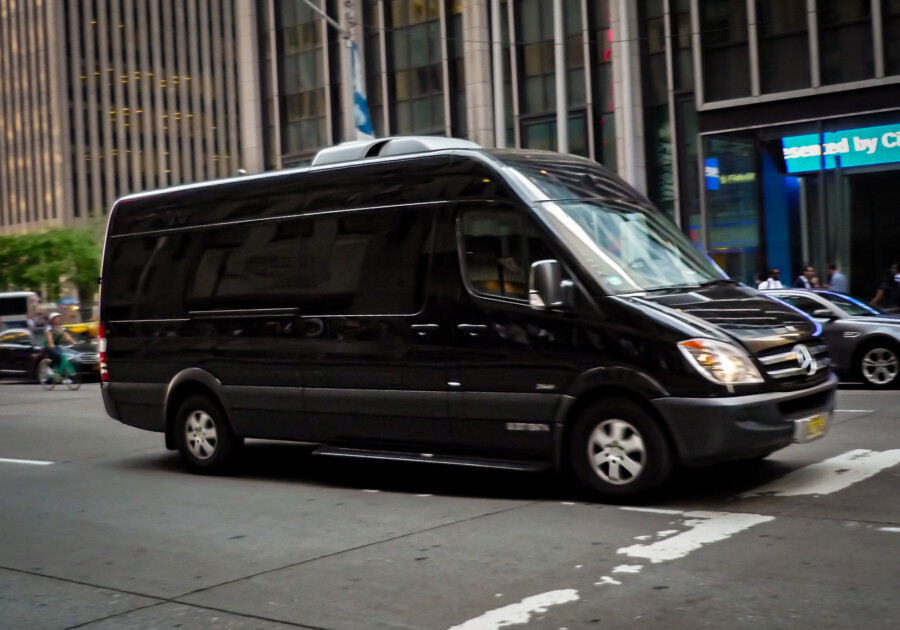 Black sprinter van driving through a downtown city