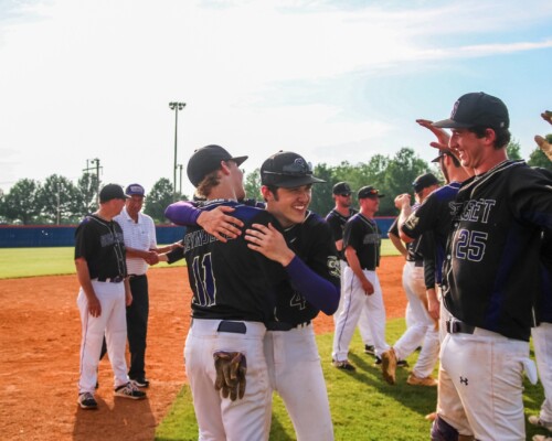 Baseball team hugging and cheering for each other on the baseball field
