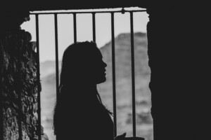 woman standing in front of prison bars